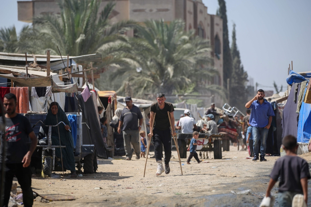 Displaced Palestinians prepare to leave the perimeter of the Al-Aqsa Martyrs Hospital in Deir al-Balah in the central Gaza Strip following renewed Israeli evacuation orders for the area on August 26, 2024. (Photo by Eyad Baba / AFP)

