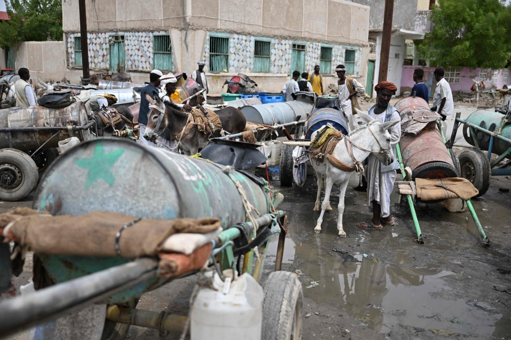 Sudanese queue to fill on water Port Sudan on August 26, 2024, after a dam collapsed as a result of heavy rain. (Photo by Ibrahim ISHAQ / AFP)
