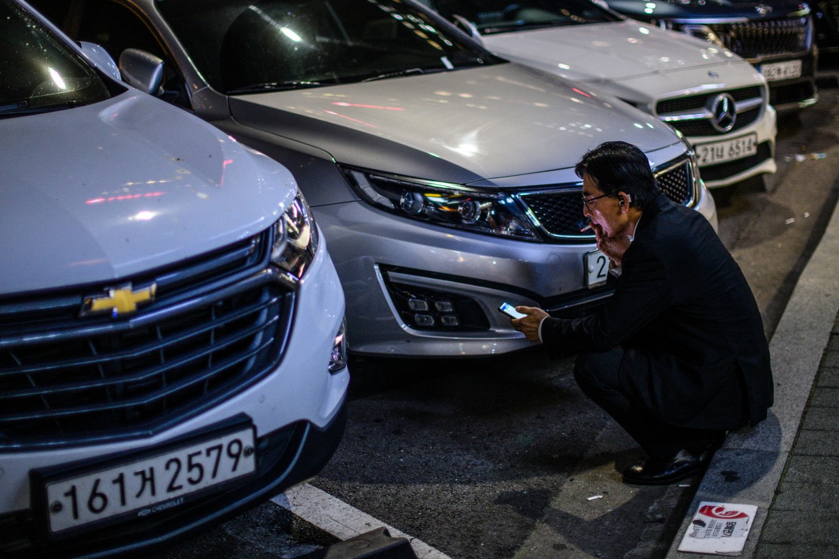 A man sits near parked cars along a road in Seoul on August 20, 2024. (Photo by ANTHONY WALLACE / AFP)
