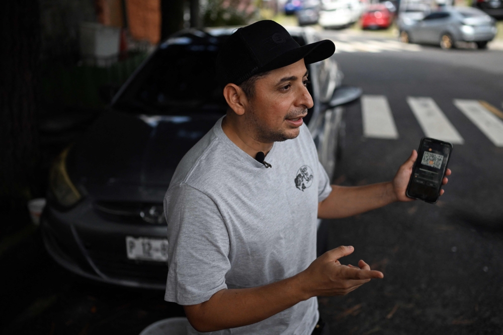Taxi driver Napoleon Osorio shows an app on his phone that he uses to charge his rides in bitcoins in San Salvador on September 4, 2024. (Photo by Marvin Recinos / AFP)