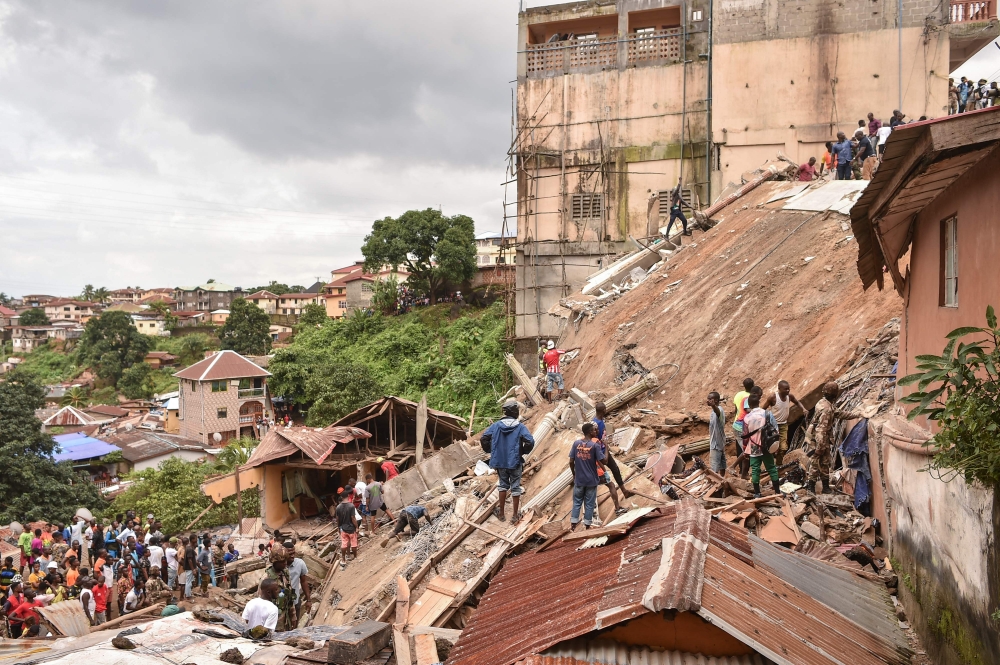 Rescue workers search through rubbles for survivors after a seven story building collapsed in Freetown on September 16, 2024. (Photo by Saidu Bah / AFP)