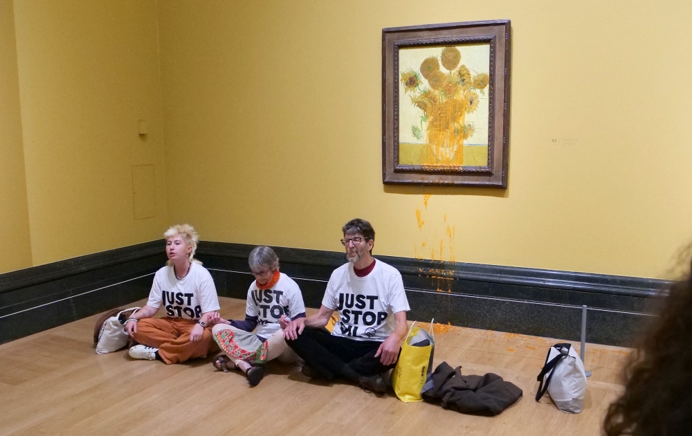 A handout picture from the Just Stop Oil climate campaign group shows three activists sitting on the floor under Vincent van Gogh's 