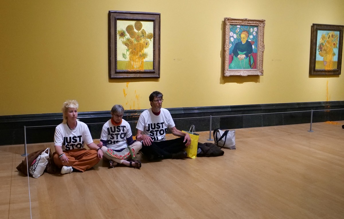 A handout picture from the Just Stop Oil climate campaign group shows three activists sitting on the floor under Vincent van Gogh's 