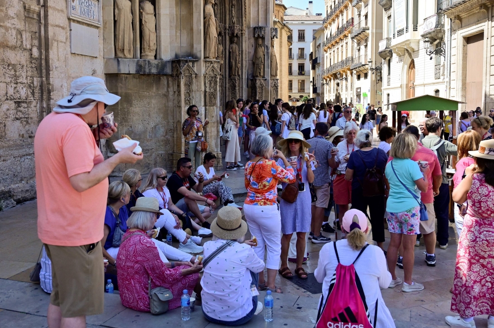 A group of tourists take a snack in a street of Valencia on July 5, 2024. Photo by Jose Jordan / AFP