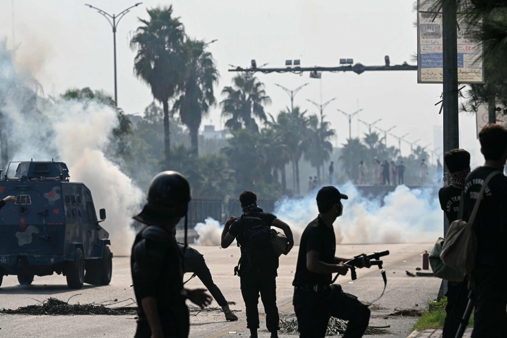 Policemen fire tear gas shells to disperse supporters of jailed former prime minister Imran Khan's Pakistan Tehreek-e-Insaf (PTI) party during a protest in Islamabad on October 5, 2024. (Photo by FAROOQ NAEEM / AFP)
