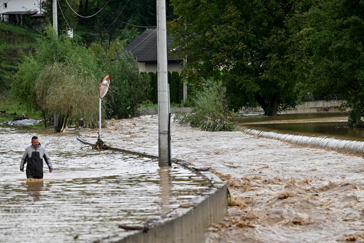 A man walks in the water along a flooded road following heavy rains in the town of Kiseljak, about twenty kilometres west of Sarajevo on October 4, 2024. Photo by Elvis BARUKCIC / AFP.