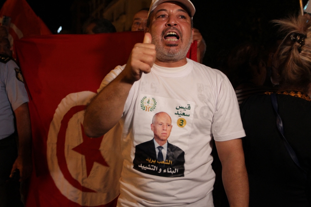 A supporter of Tunisia's President celebrates after the announcement of the first estimates in favor of the incumbent President, on the Avenue Habib Bourguiba in Tunis on October 6, 2024. (Photo by YASSINE MAHJOUB / AFP)
