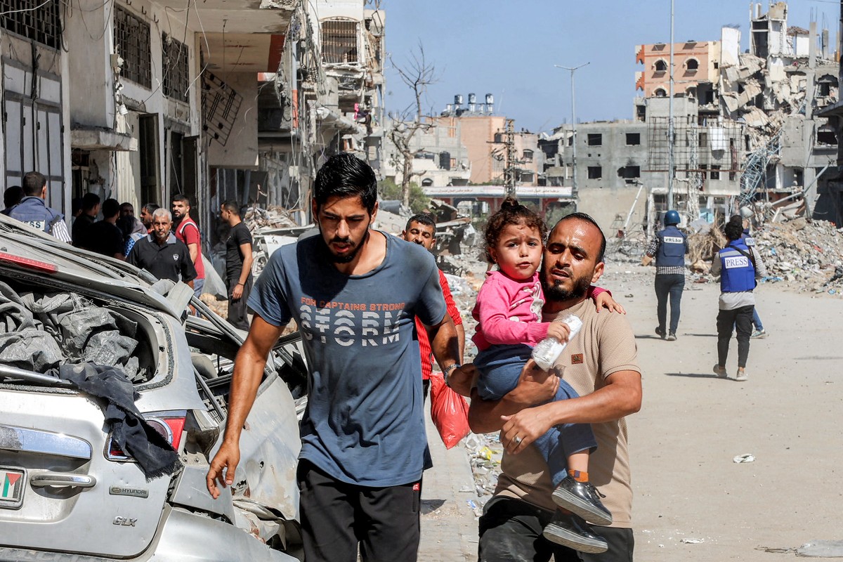 A man carries a child while evacuating in the Jabalia camp for Palestinian refugees in the northern Gaza Strip on October 9, 2024. Photo by Omar AL-QATTAA / AFP.
