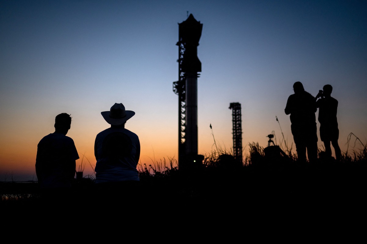 Visitors look at the SpaceX Starship as it sits on a launch pad at Starbase near Boca Chica, Texas, on October 12, 2024, ahead of the Starship Flight 5 test. (Photo by SERGIO FLORES / AFP)
