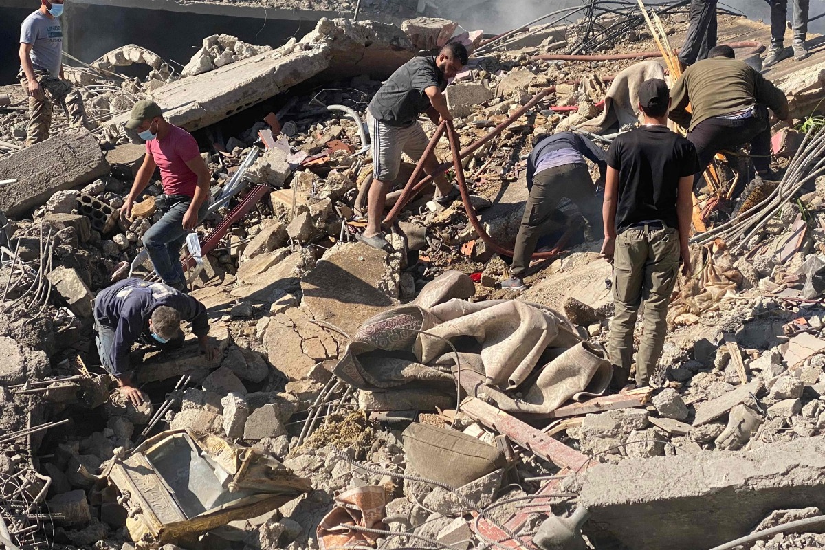 People inspect the scene of a site hit by an Israeli air strike on the village of El-Khodr in the centre of Lebanon's eastern Bekaa Valley on October 24, 2024. (Photo by Hassan SKEINE / AFP)
