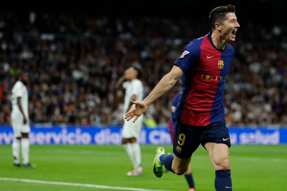 Barcelona's Polish forward #09 Robert Lewandowski celebrates scoring his team's second goal during the Spanish league football match between Real Madrid CF and FC Barcelona at the Santiago Bernabeu stadium in Madrid on October 26, 2024. (Photo by OSCAR DEL POZO / AFP)
