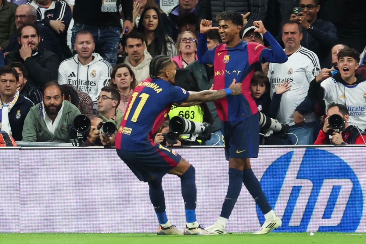 Barcelona's Spanish forward #19 Lamine Yamal (R) celebrates scoring their third goal with teammate Barcelona's Brazilian forward #11 Raphinha during the Spanish league football match between Real Madrid CF and FC Barcelona at the Santiago Bernabeu stadium in Madrid on October 26, 2024. (Photo by Pierre-Philippe MARCOU / AFP)