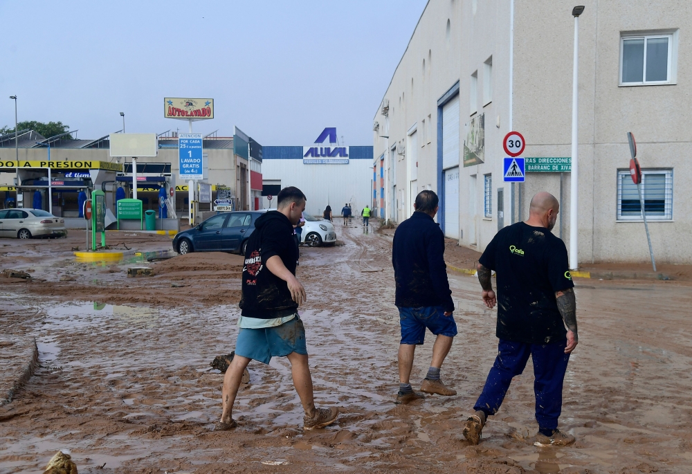 Men walk in a street covered in mud following floods in Picanya, near Valencia, eastern Spain, on October 30, 2024. (Photo by Jose Jordan / AFP) 