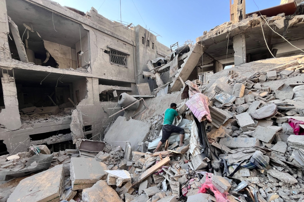 A Palestinian man searches for missing family members under the rubble outside the Assi building which was destroyed in Israeli bombardment in Beit Lahia in the northern Gaza Strip on November 7, 2024. (Photo by AFP)