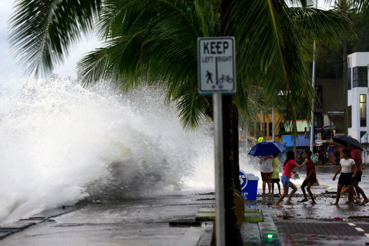 People (R) react as large waves break along a seawall ahead of the expected landfall of Super Typhoon Man-yi, in Legaspi City, Albay province on November 16, 2024. (Photo by CHARISM SAYAT / AFP)
