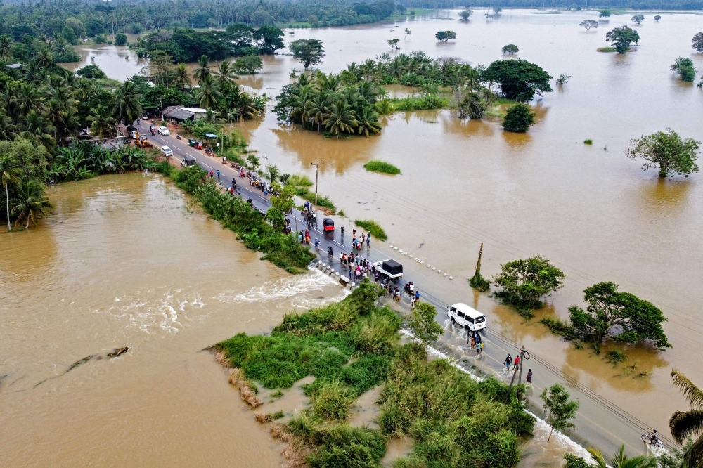 People walk along a street at a neighborhood partially submerged in floodwater as cyclone Fengal is forecasted to make landfall in Puttalam on November 29, 2024. (Photo by AFP)
