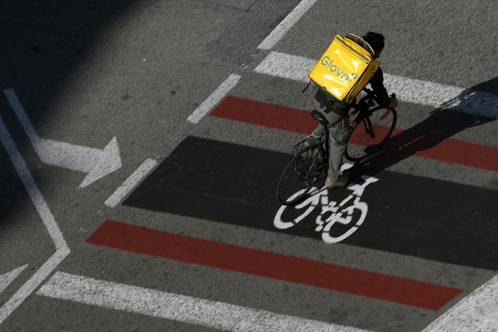 (Files) A Glovo delivery worker rides in Barcelona on February 4, 2021. (Photo by Lluis Gene / AFP)