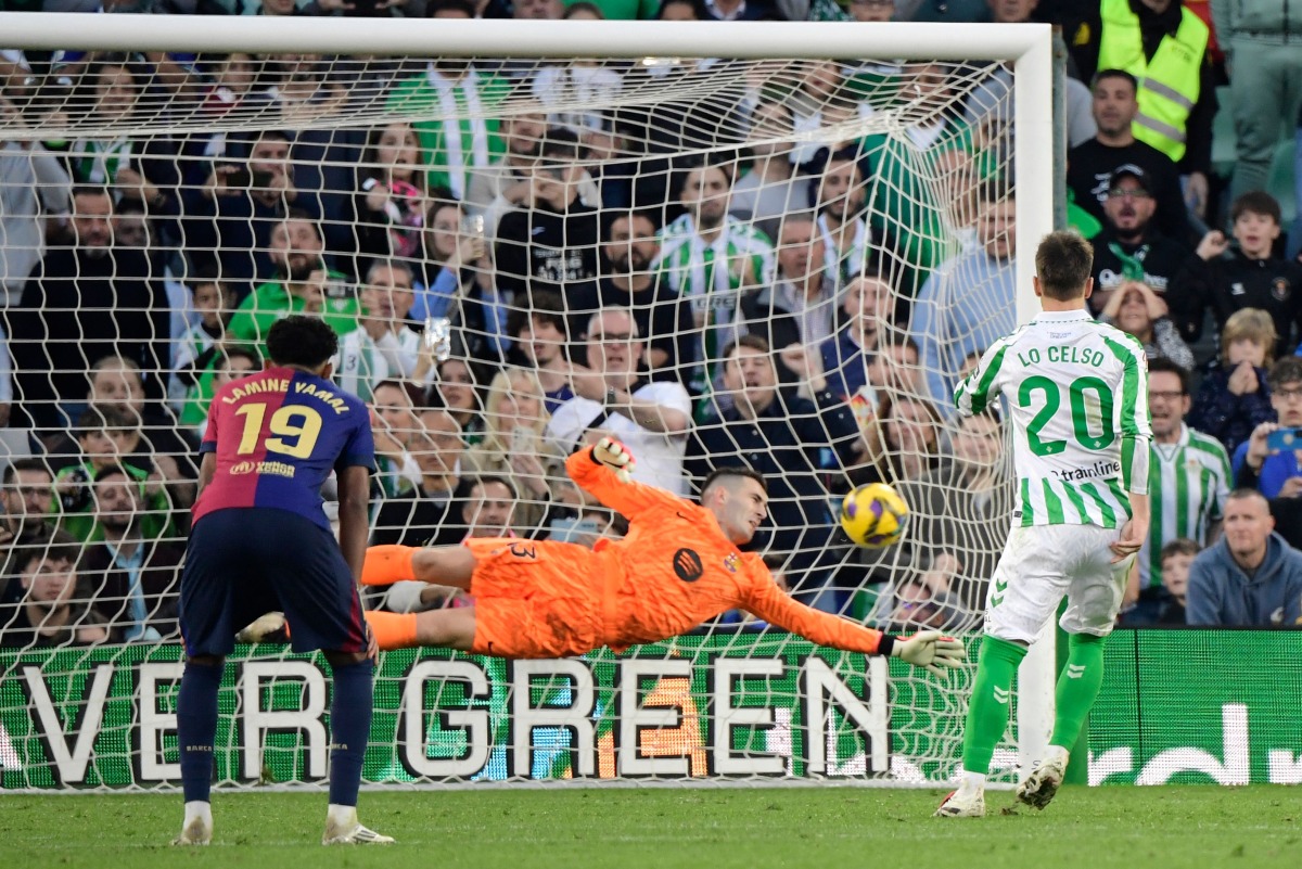 Real Betis' Argentine midfielder #20 Giovani Lo Celso scores his team's first goal from the penalty spot during the Spanish league football match between Real Betis and FC Barcelona at the Benito Villamarin stadium in Seville on December 7, 2024. (Photo by CRISTINA QUICLER / AFP)
