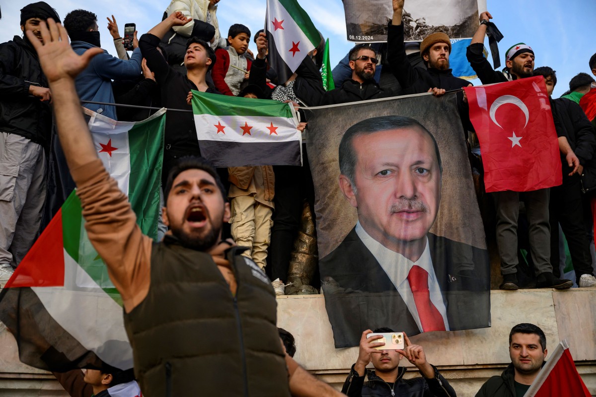 People hold a banner featuring Turkish President Recep Tayyip Erdogan as members of the Syrian community and supporters gather to celebrate the fall of Syrian president Bashar al-Assad in the face of an offensive by Islamist-led rebels, in Istanbul on December 8, 2024. Photo by Yasin AKGUL / AFP.