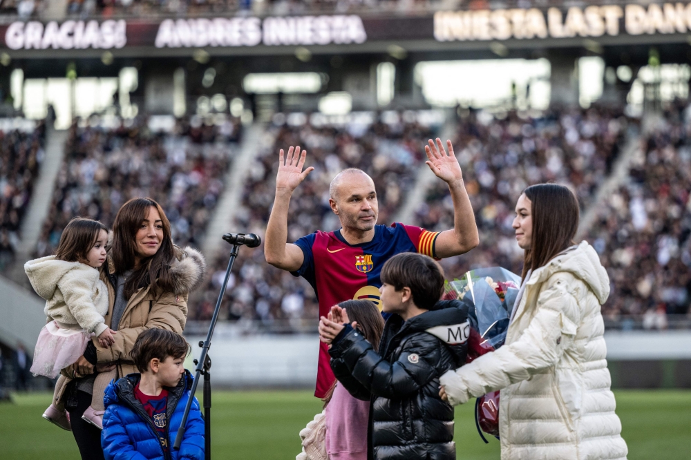 Spanish football legend Andres Iniesta (C) gestures as he is joined by his wife Anna Ortiz and his five children during his retirement ceremony after the exhibition football match between former Barcelona and Real Madrid players -- Barca Legends and Real Madrid Leyendas -- at Ajinomoto Stadium in Tokyo on December 15, 2024. (Photo by Philip Fong / AFP)
