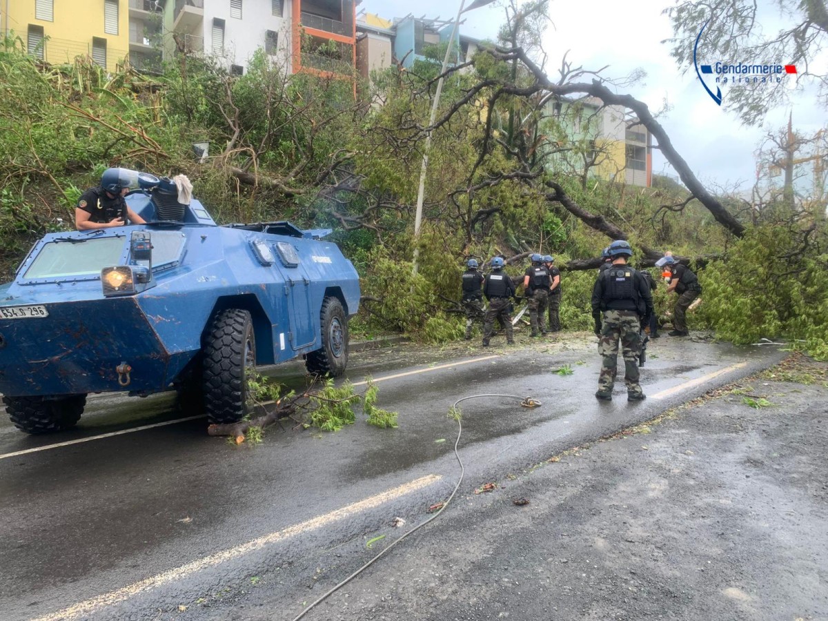 This handout photograph released by the Gendarmerie nationale on December 15, 2024 and taken on that day at an undisclosed location on the French Indian Ocean territory of Mayotte shows French gendarmes near their armored vehicle Berliet VXB-170 (or VBRG) as they work to remove an unrooted tree from a road, a day after the cyclone Chido hit the archipelago. Photo by Handout / GENDARMERIE NATIONALE / AFP.