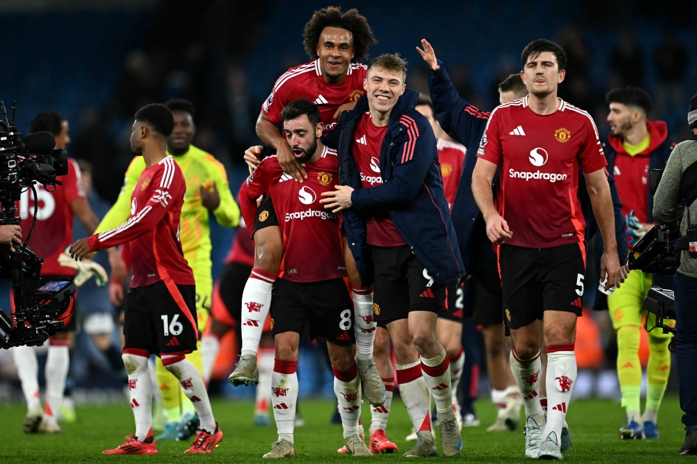 Manchester United's Portuguese midfielder #08 Bruno Fernandes (2nd left) Manchester United's Dutch striker #11 Joshua Zirkzee (centre) and Manchester United's Danish striker #09 Rasmus Hojlund (2nd right) celebrate following the English Premier League football match between Manchester City and Manchester United at the Etihad Stadium in Manchester, north west England, on December 15, 2024. (Photo by Paul Ellis / AFP)
