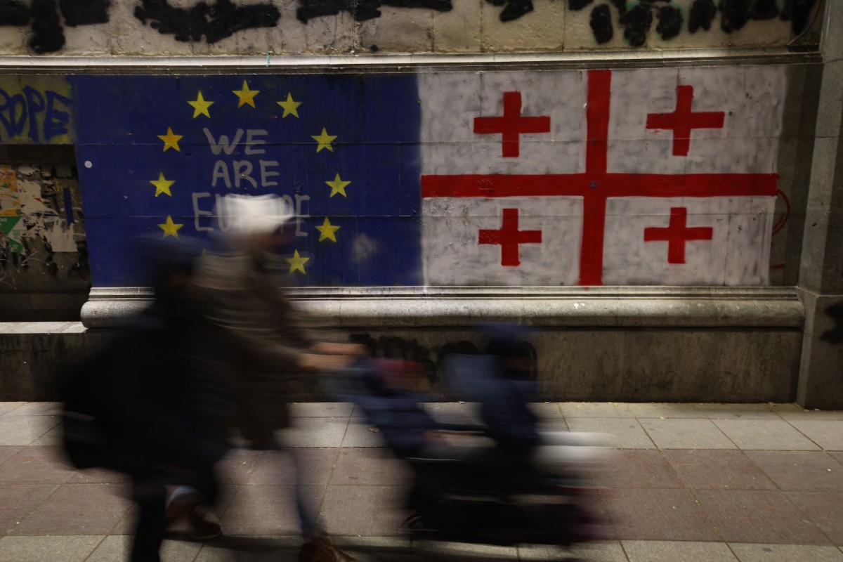 Photo used for representational purposes. Georgia; people walk by outside the Georgian parliament after the parliament members elected a new president, in Tbilisi on December 15, 2024. Photo by Giorgi ARJEVANIDZE / AFP.