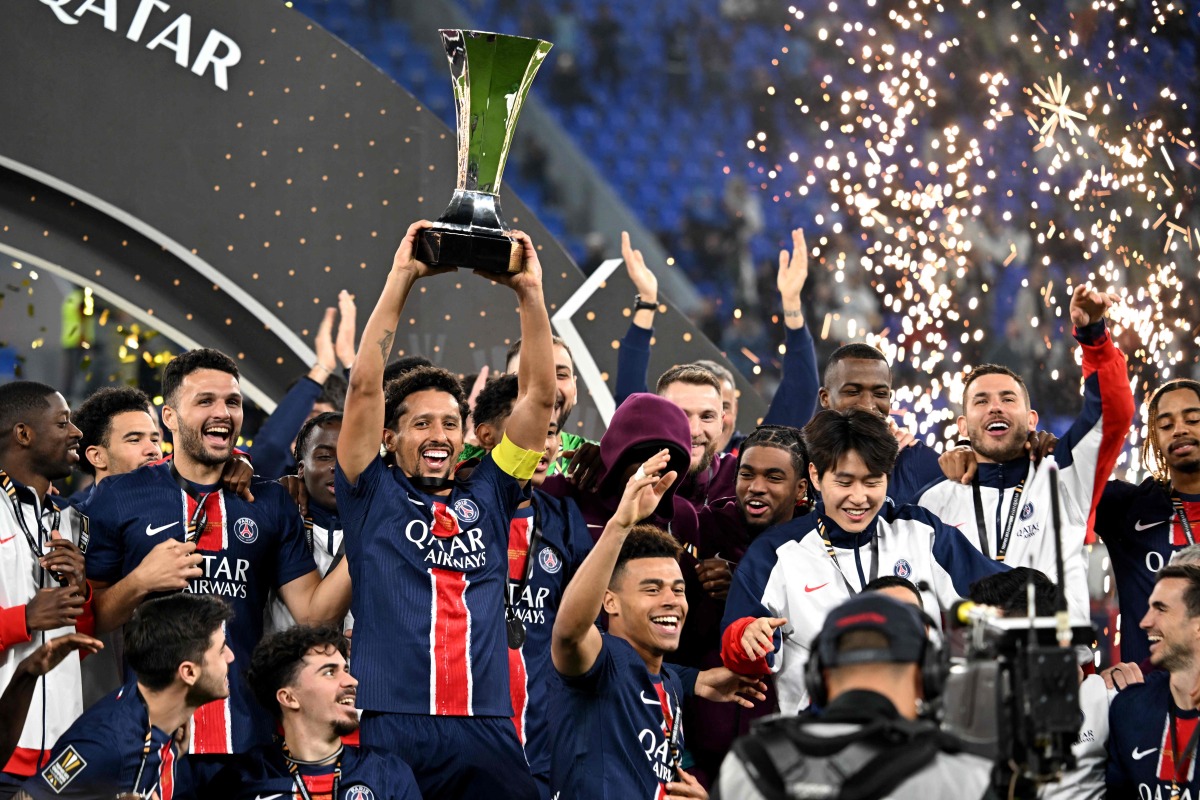Paris Saint-Germain players celebrate with the trophy after winning the French Champions' Trophy (Trophee des Champions) final football match between Paris Saint-Germain (PSG) and AS Monaco (ASM) at the Stadium 974 in Doha on January 5, 2025. (Photo by Mahmud HAMS / AFP)