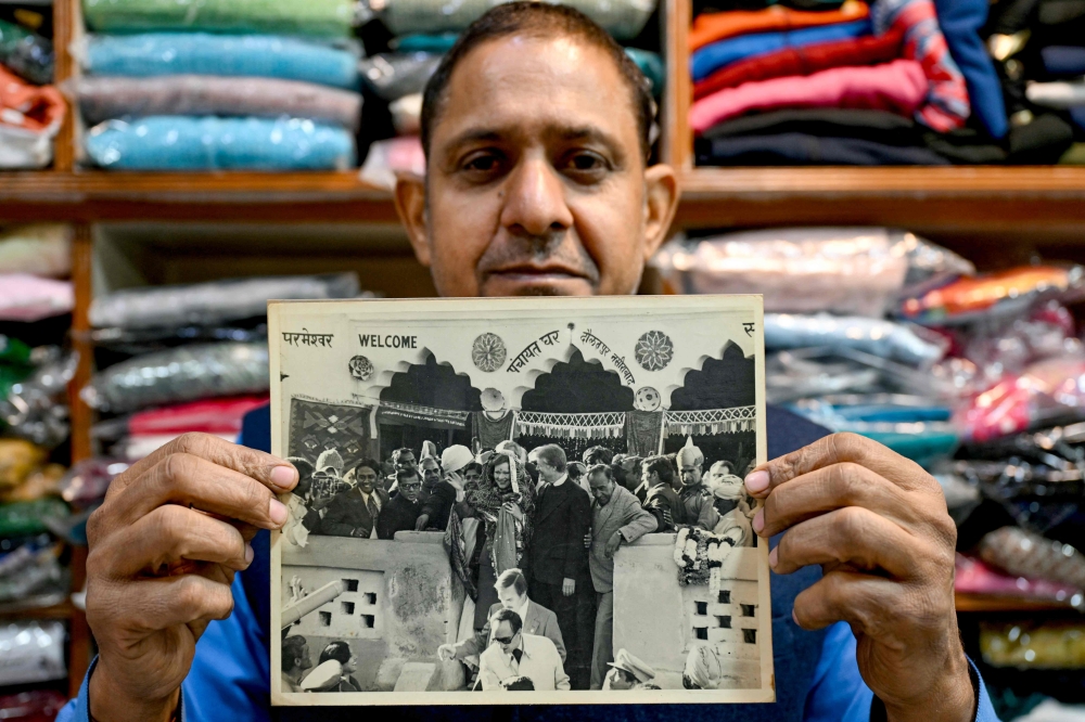 Resident Rajiv Kumar shows a photograph at his shop near Carterpuri village in Gurgaon on January 7, 2025, picturing late former US president Jimmy Carter and his wife Eleanor Rosalynn Carter during their visit to the eponymous village in 1978. (Photo by Money Sharma / AFP)