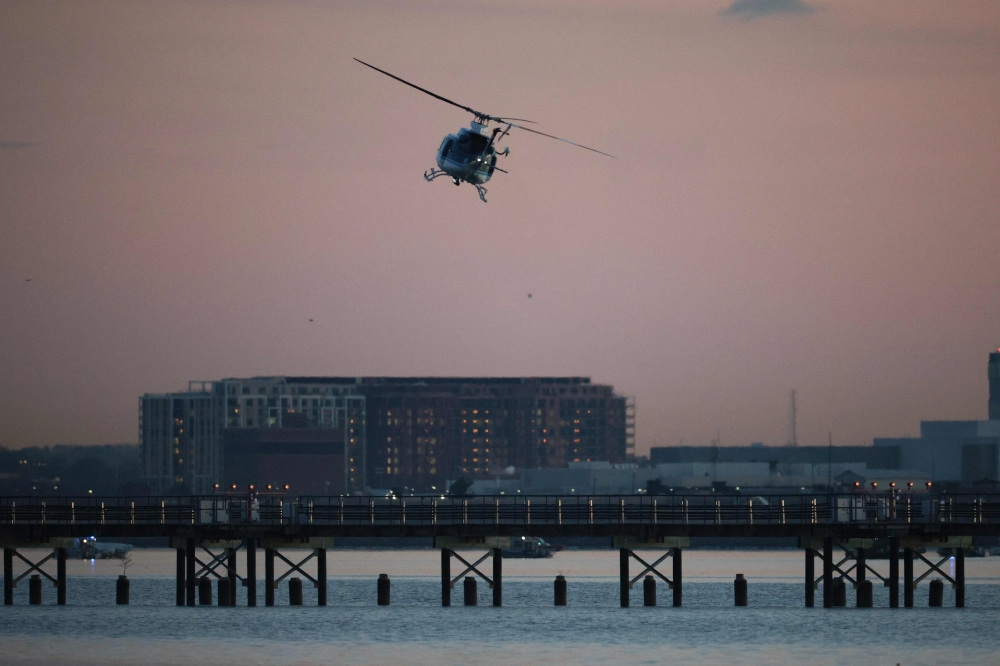 A helicopter flies near the crash site of the American Airlines plane on the Potomac River on January 30, 2025 in Arlington, Virginia. Win McNamee/Getty Images/AFP