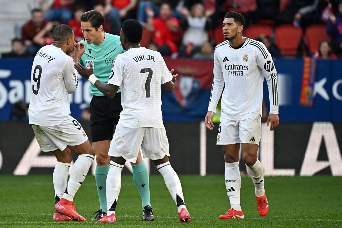 Real Madrid's French forward #09 Kylian Mbappe and Real Madrid's Brazilian forward #07 Vinicius Junior remonstrate with Spanish referee Munuera Montero about the red card presented to Real Madrid's English midfielder #05 Jude Bellingham (R) during the Spanish league football match between CA Osasuna and Real Madrid CF at El Sadar Stadium in Pamplona on February 15, 2025. (Photo by ANDER GILLENEA / AFP)
