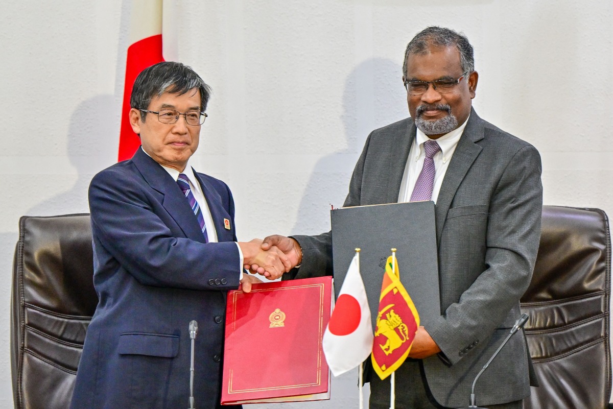 Japan's ambassador to Sri Lanka Akio Isomata (L) and Secretary to Sri Lanka's finance ministry Mahinda Siriwardana shake hands after signing of debt restructuring agreements between two governments in Colombo on March 7, 2025. Photo by Ishara S. KODIKARA / AFP