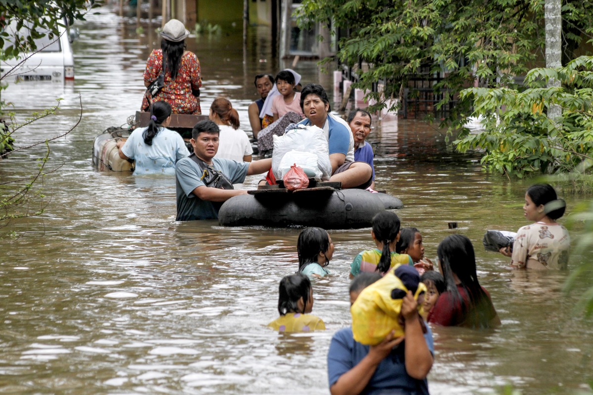People wade through flood water after heavy rain and overflow of Siak River in Pekanbaru, Riau province, Indonesia, March 6, 2025. (Photo by Hadly Vavaldi/Xinhua)
