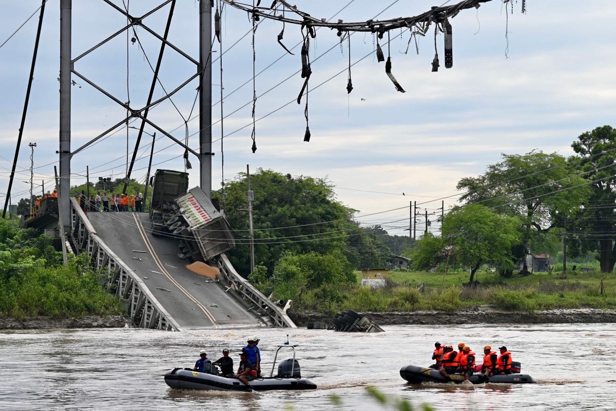 In this aerial view rescuers search for missing persons after a suspension bridge collapsed in Duale, Guayas province, Ecuador on March 20, 2025. The collapse in Ecuador of a busy 200-metre-long suspension bridge carrying several vehicles left at least one dead, five injured and two missing, authorities said in a new assessment on Thursday. (Photo by MARCOS PIN / AFP)
