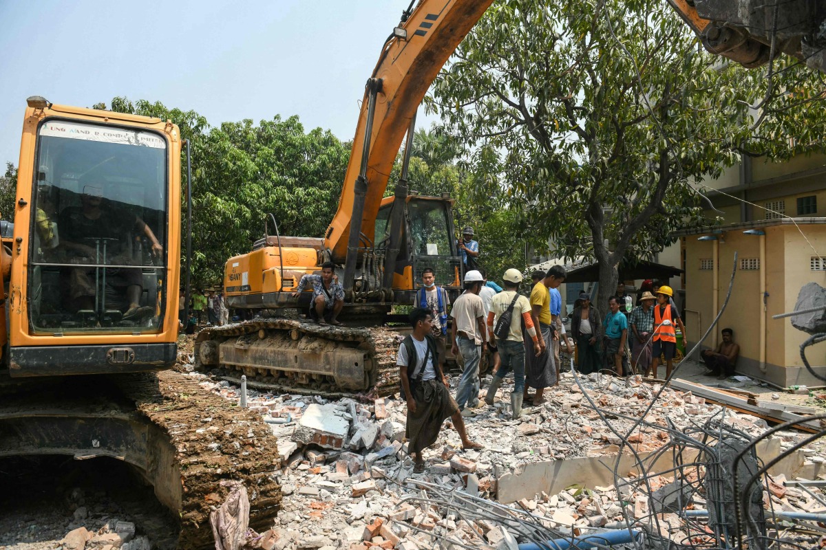 Heavy construction equipment is used to dig through the rubble as people look for survivors in a destroyed building in Mandalay on March 29, 2025, a day after an earthquake struck central Myanmar. Rescuers dug through the rubble of collapsed buildings on March 29 in a desperate search for survivors after a huge earthquake hit Myanmar and Thailand, killing more than 1000 people. (Photo by Sai Aung MAIN / AFP)
