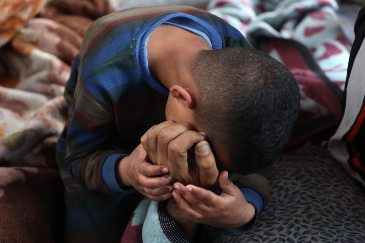 A boys mourns over the body of a loved one killed in overnight Israeli bombardment on northen Gaza, at the Ahli Arab Hospital, also known as the Maamadani (Baptist) Hospital, in Gaza City on April 3, 2025. (Photo by Omar AL-QATTAA / AFP)