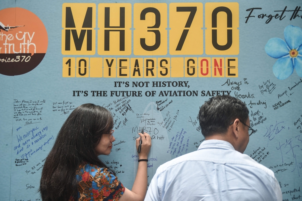 (Files) A woman writes a message during an event held by relatives of the passengers and supporters to mark the 10th year since the Malaysia Airlines flight MH370 disappeared from radar, in Subang Jaya on March 3, 2024. (Photo by Arif Kartono / AFP)

