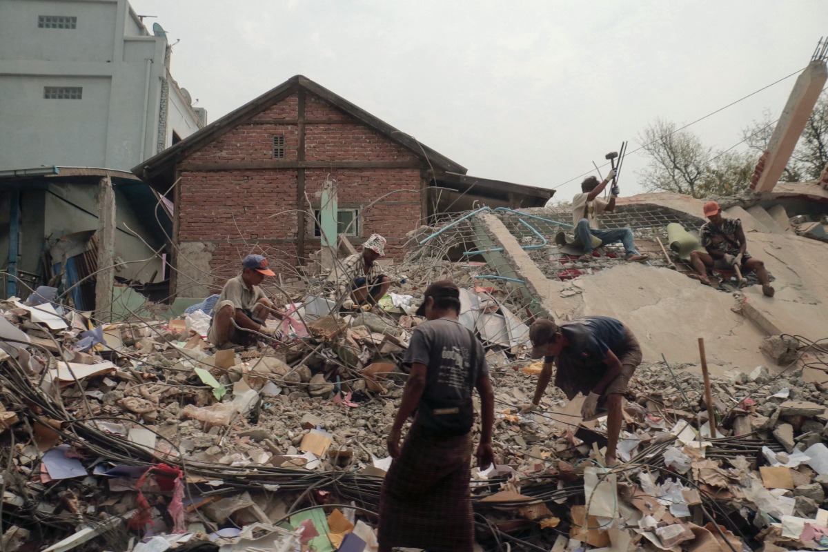 People sort through the rubble of a collapsed building in Mandalay on April 5, 2025, following the March 28 earthquake. Photo by Zaw Htun / AFP.
