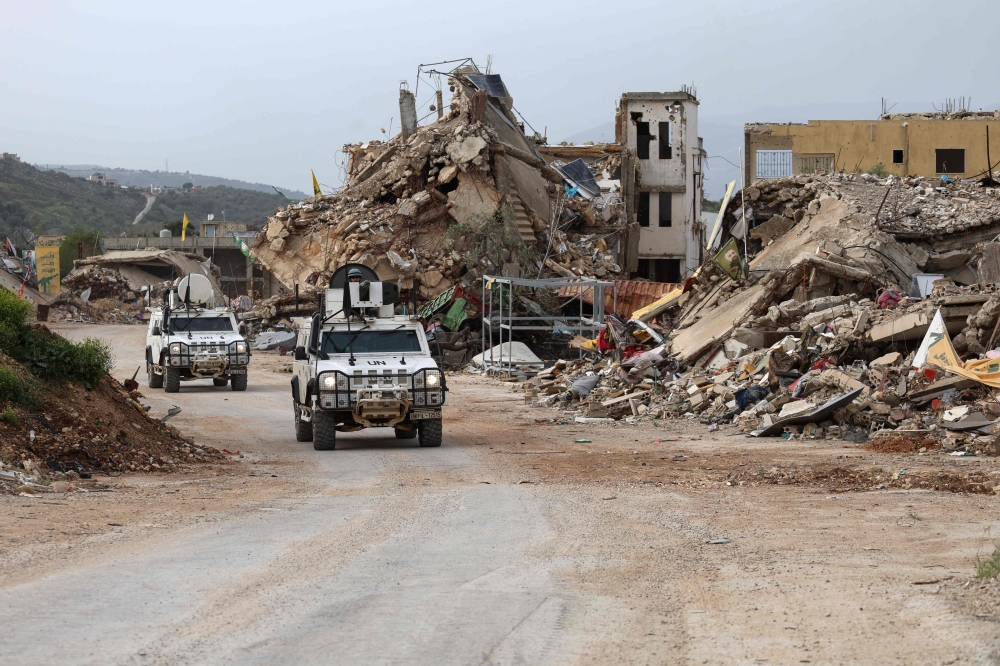 United Nations peacekeepers drive in vehicles of the UN Interim Force in Lebanon (UNIFIL) past destroyed buildings while patroling in Lebanon's southern village of Kfar Kila close to the border with Israel on April 6, 2025. (Photo by Rabih Daher / AFP)