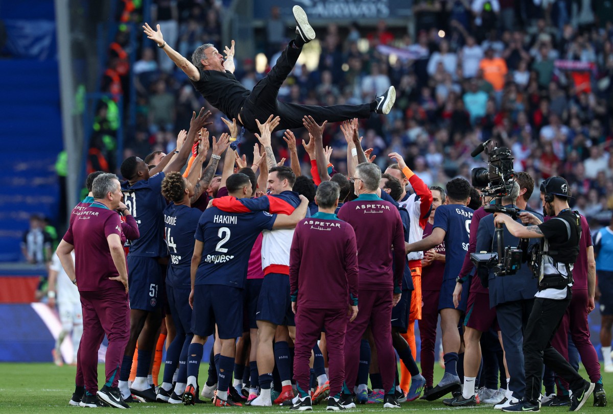 Paris-Saint Germain's players throw up in the air headcoach Luis Enrique as they celebrate after winning the match and the French championship title at The Parc des Princes Stadium in Paris on April 5, 2025. (Photo by Franck Fife / AFP)
