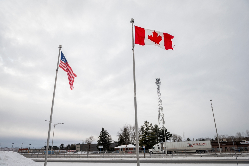 (Files) The Canadian and US flags fly near the Canada-US border in Blackpool, Quebec, Canada, on February 2, 2025. (Photo by Andrej Ivanov / AFP)