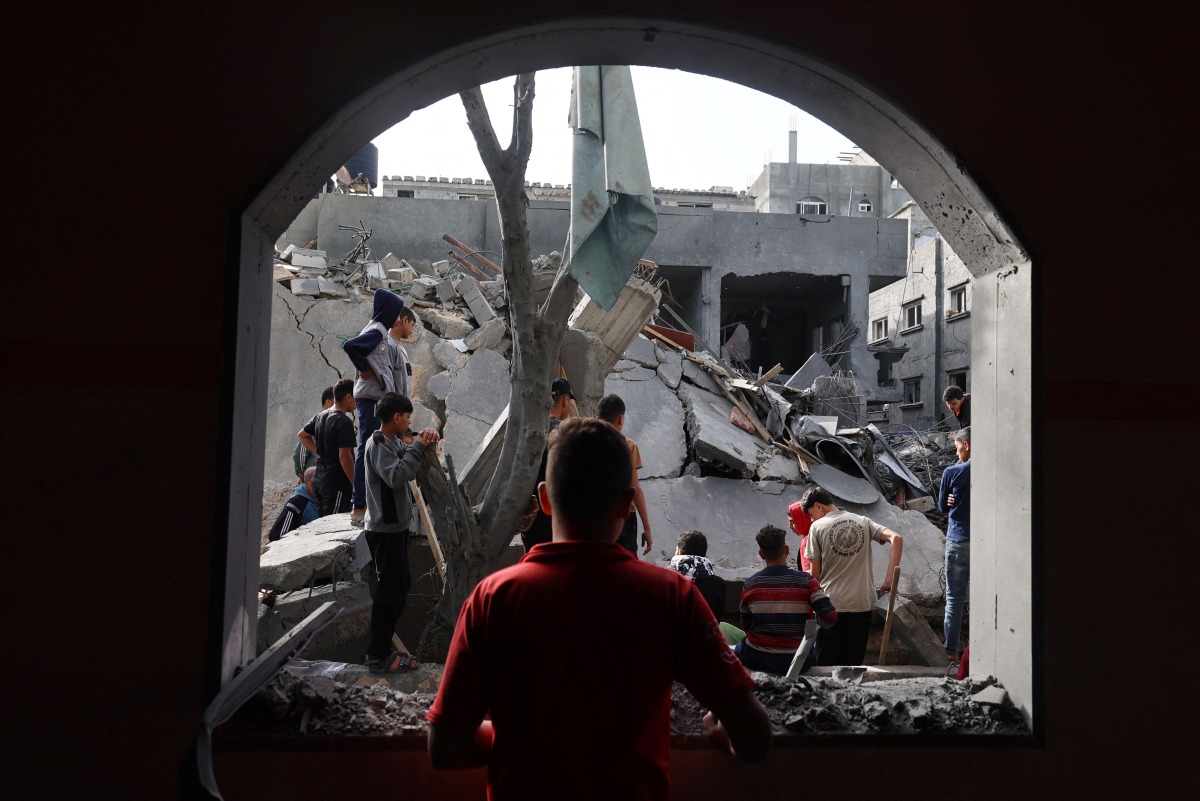 Children look at the destruction in a residential area in Deir al-Balah in the central Gaza Strip on April 7, 2025, following overnight Israeli airstrikes targeting the area. (Photo by Eyad BABA / AFP)
