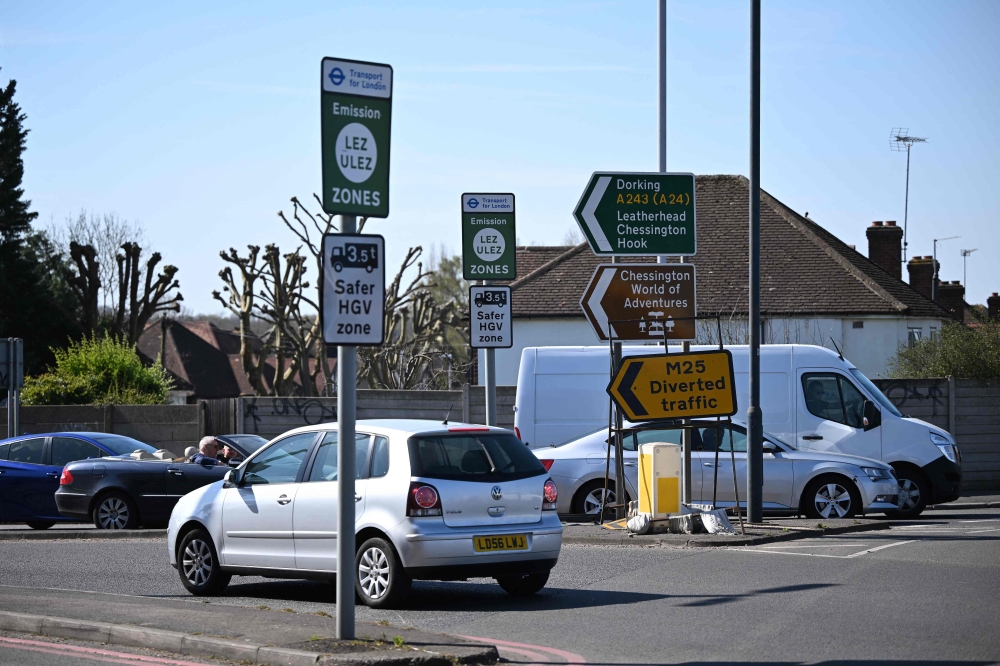 A photograph taken on April 2, 2025 shows signs indicating the ultra-low emission zone (ULEZ) in Hook, south west London. (Photo by Justin Tallis / AFP)
