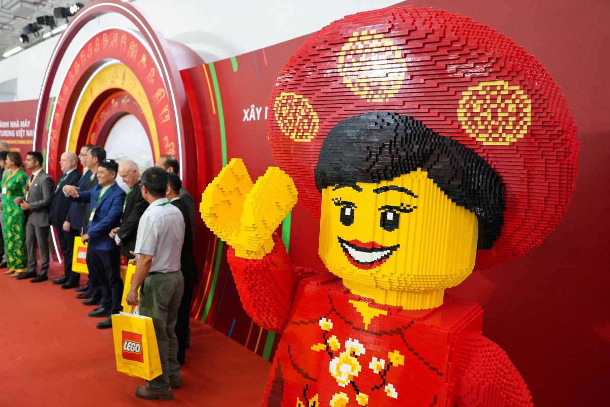 Attendees take photos past a full-scale model made with Lego bricks during the inauguration of the Lego factory in Binh Duong Province on April 9, 2025. Photo by Huu Khoa / AFP