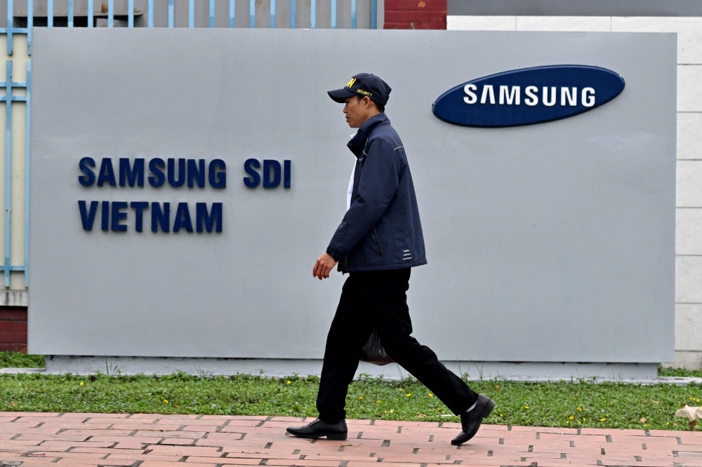 This photo taken on April 8, 2025 shows a man walking past the logo of Samsung Electronics on a billboard in Bac Ninh province. (Photo by Nhac Nguyen / AFP) 