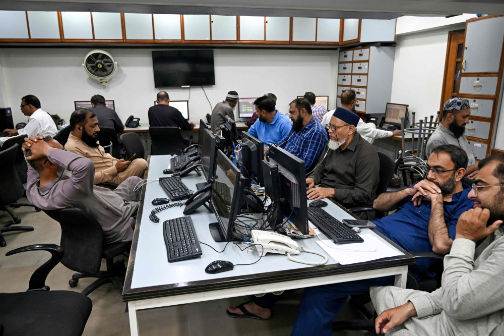 Stockbrokers monitor share prices on computers during a trading session at the Pakistan Stock Exchange (PSX) in Karachi on April 9, 2025.  (Photo by Rizwan Tabassum / AFP)

