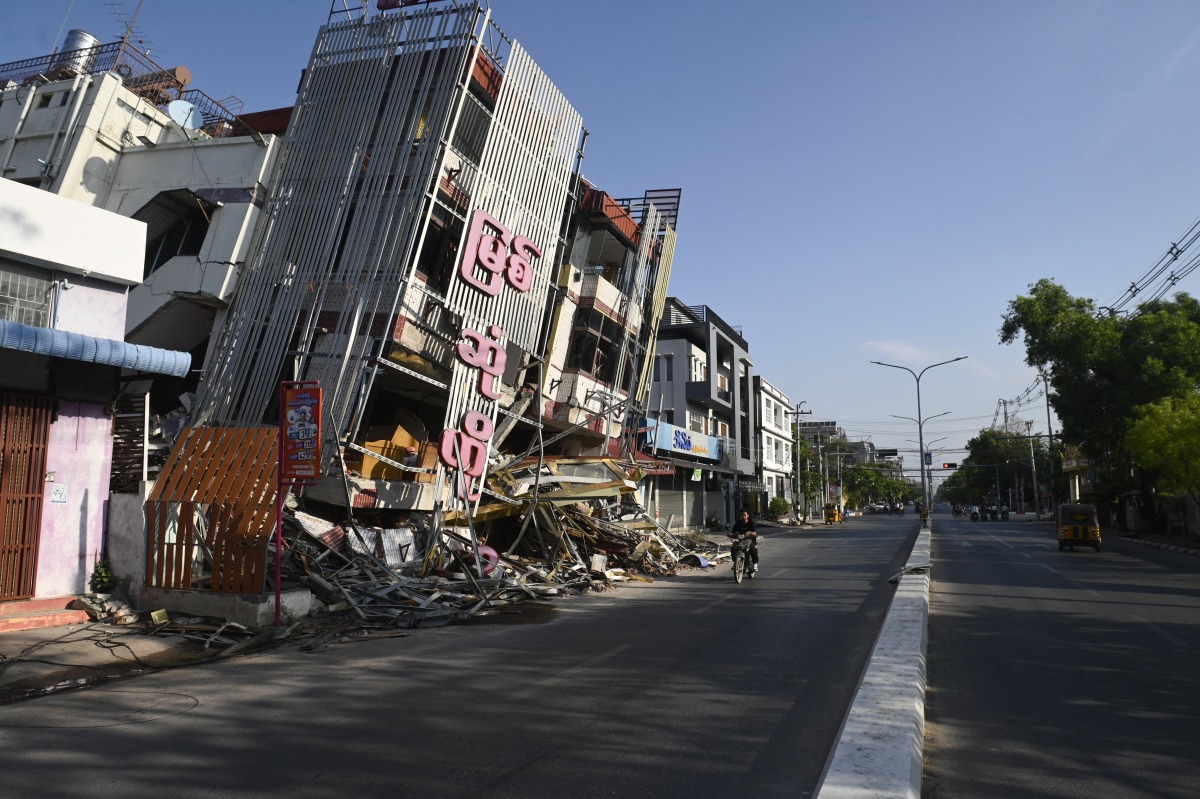 A man on motorcycle rides past a damaged building in Mandalay on April 13, 2025, following the devastating March 28 earthquake. Photo by Sai Aung MAIN / AFP
