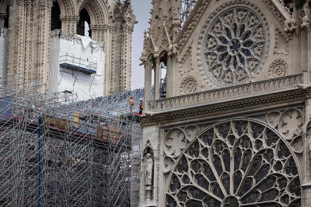 (Files) Workers operate on scaffoldings during reconstruction works around the wooden structure of the Notre-Dame de Paris Cathedral, in Paris on July 4, 2024. (Photo by Joel Saget / AFP)