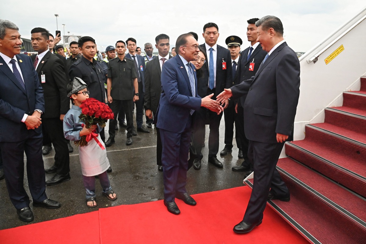 This handout photo taken and released by Malaysia's Department of Information on April 15, 2025 shows Malaysia's Prime Minister Anwar Ibrahim (C) shaking hands with China's President Xi Jinping (R) upon his arrival at the Bunga Raya VIP complex of Kuala Lumpur International Airport in Sepang. (Photo by Farhan ABDULLAH / MALAYSIA'S DEPARTMENT OF INFORMATION / AFP)