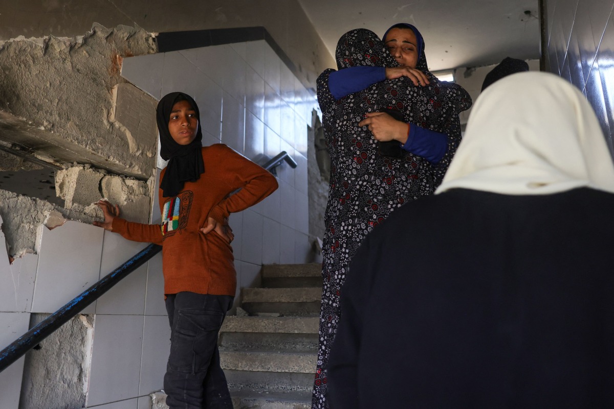 Palestinian women mourn and hug one another after an Israeli strike on a school housing displaced Palestinians in Jabalia in the northern Gaza Strip on April 17, 2025. (Photo by BASHAR TALEB / AFP)
